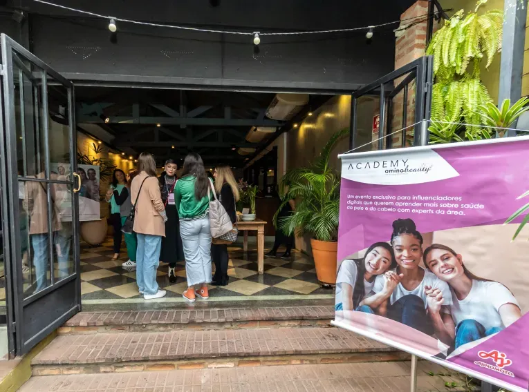 Pessoas reunidas na entrada do local do evento com um banner exibindo o logo ‘Academy AminoBeauty’