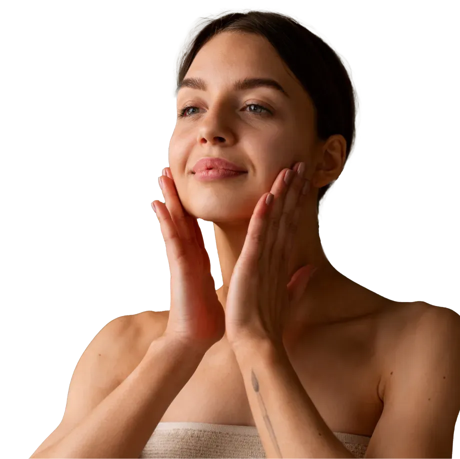 Mulher realizando uma massagem facial em uma rotina de cuidados com a pele. Ela veste uma toalha, transmitindo sensação de limpeza e bem-estar.